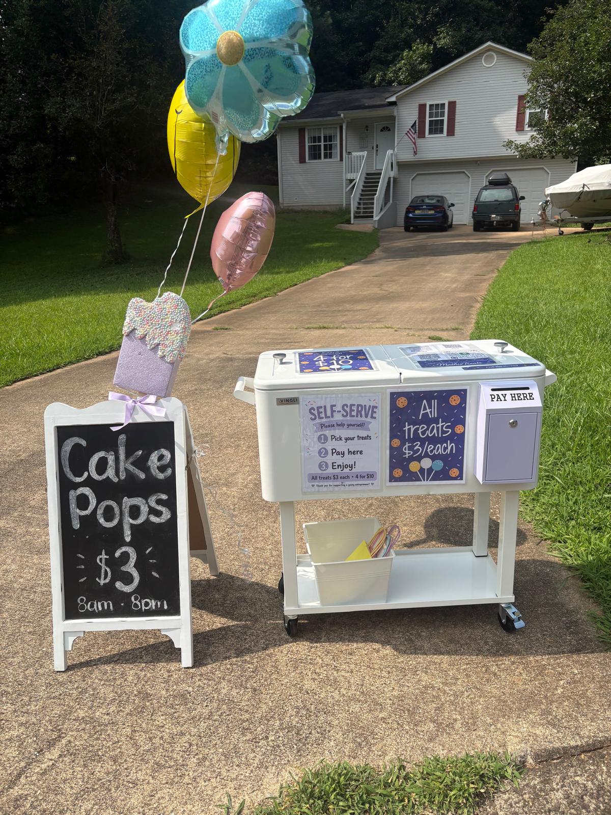 Mathias Treats outdoor display with balloons and a cakesicle sign