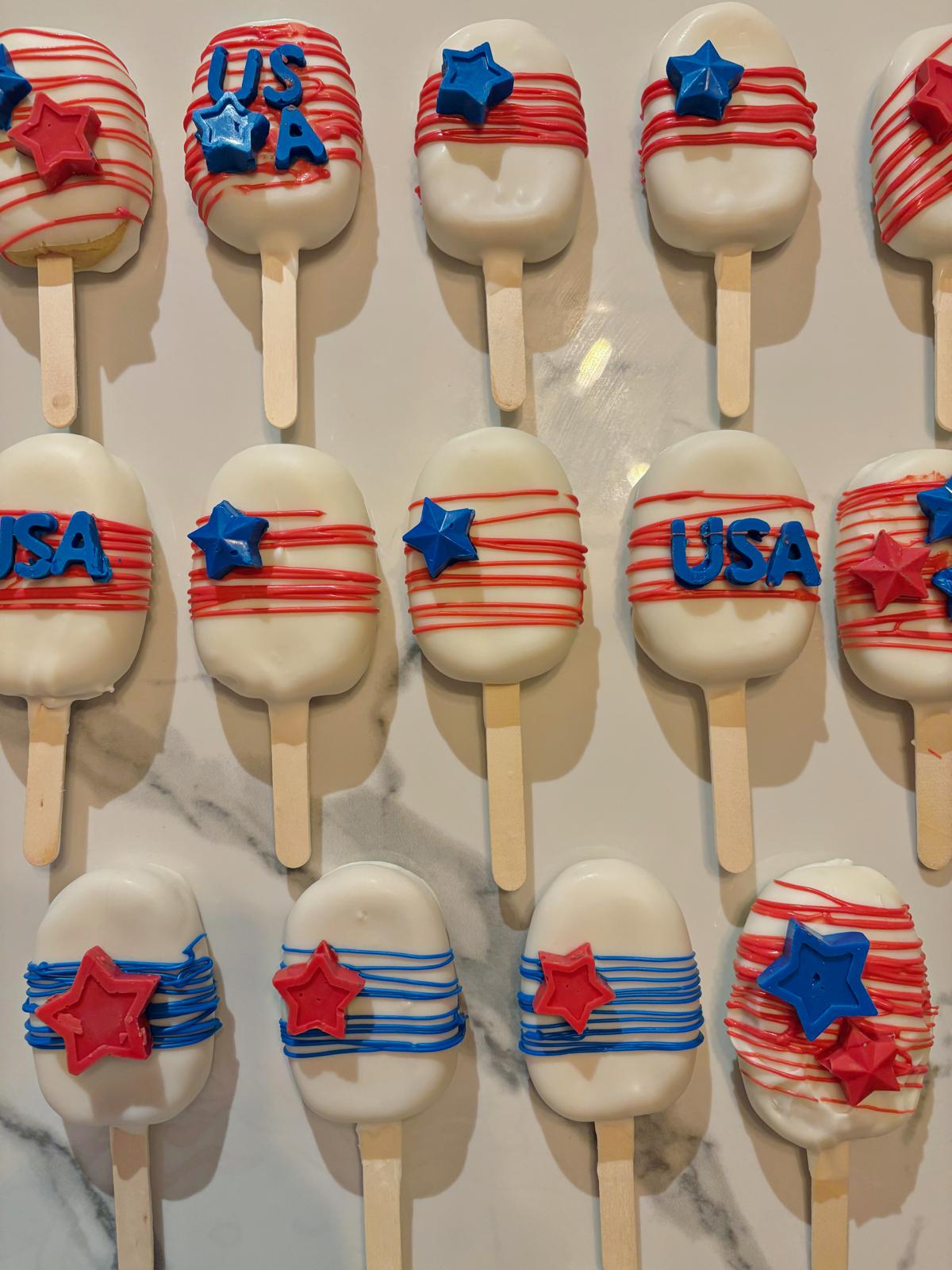 Tray of red white and blue decorated cakesicles