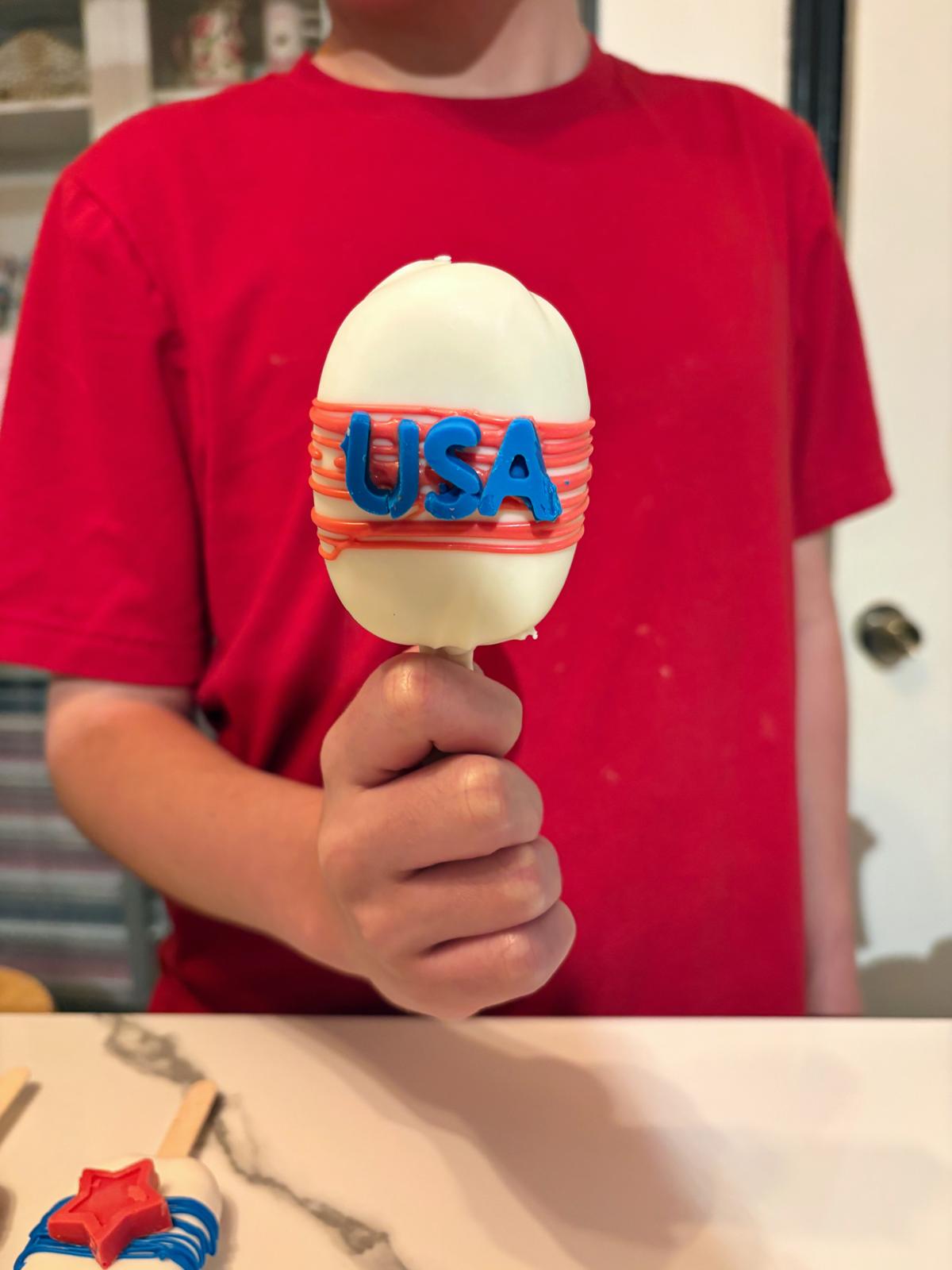 Child holding a red white and blue USA cakesicle
